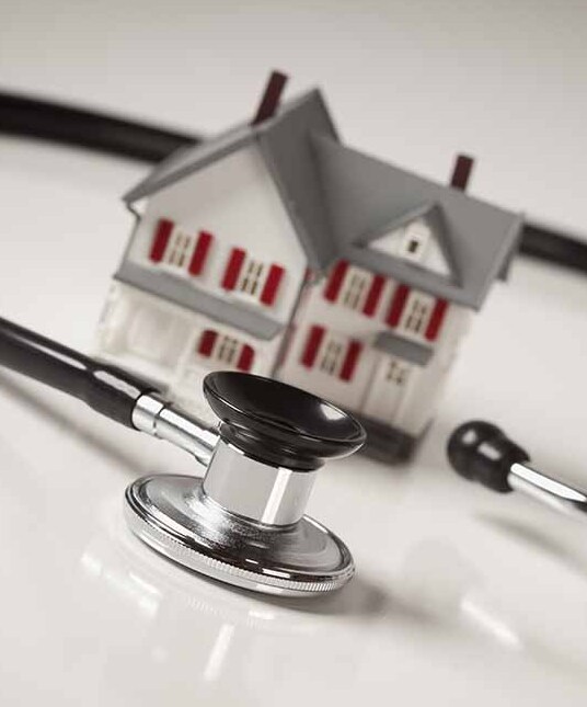 Stethoscope and Model House on Gradated Background with Selective Focus.