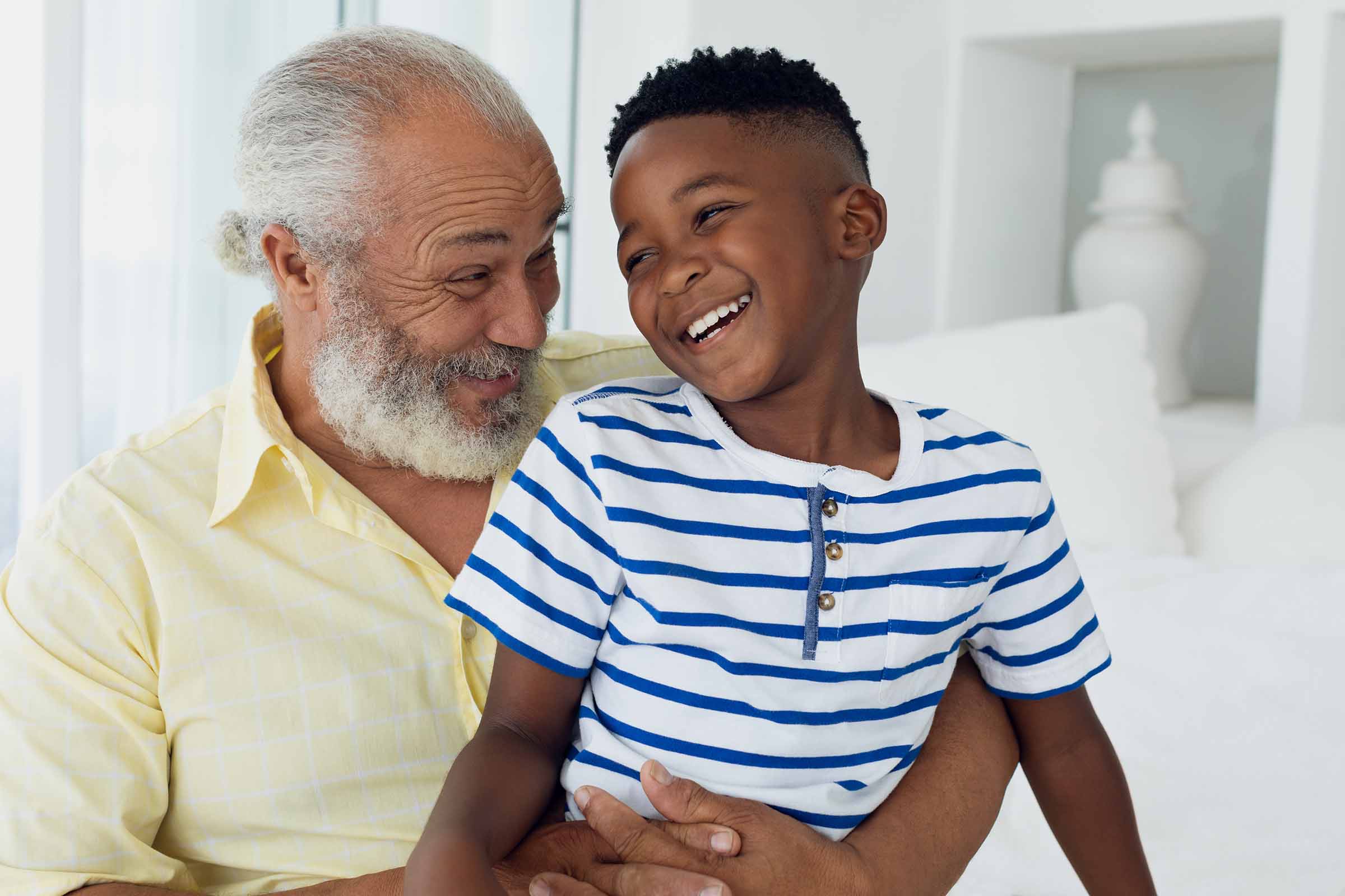 Portrait of African-American child and grandfather smiling together in a room. Authentic Senior Retired Life Concept